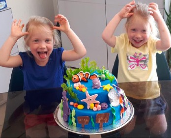 Après : Zoé et sa sœur devant le gâteau fait par Jennifer, élève de Dita